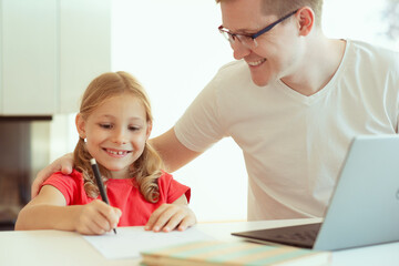 Wall Mural - Young father at home office helping daughter with online learning at homeschooling