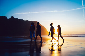 Group of friends walking on beach at sundown