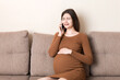 © sosiukin - pregnancyexpectation concept. happy pregnant woman talking on smartphone at home