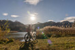 senior woman with electric mountain bike in bright backlit sun on the shore of lake Weissensee near city of Fuessen, eastern Allgaeu, Bavarian alps