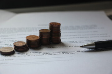 Pen and coins stacks reminding growth diagramm on agreement background. Successfully Growing Business concept