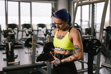 Wall Mural - tattooed woman preparing for power lifting in gym