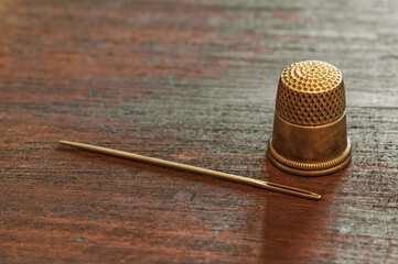 A sewing needle and an antique gold thimble.