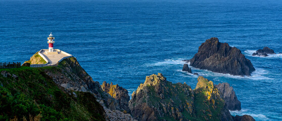 Poster - panorama of the Cabo Ortegal lighthouse in Galicia with green cliffs and sunlight and deep blue ocean