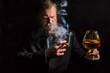© idea_studio - Solid confident bearded man in suit with glass of whisky and cigar with fume