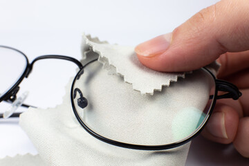 Wall Mural - Woman cleaning reading glasses with cloth. Close up photo.