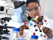 © Andrew Brookes/Westend61 - Biotechnology Research, female scientist examining a chemical formula using a ball and stick molecular model in the laboratory
