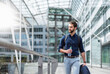 © Daniel Ingold/Westend61 - Young businessman on the go at building with glass facade