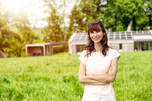 Portrait Of Smiling Woman Standing On Meadow In Front Of A House