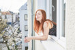 © Jo Kirchherr/Westend61 - Portrait of redheaded woman with eyes closed leaning out of window