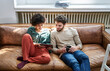 © Jo Kirchherr/Westend61 - Young man and young woman sitting on couch with cup of coffee and tablet