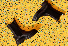 Pair Of Black Leather Boots On Yellow Terrazzo Pattern
