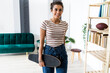 © Giorgio Fochesato/Westend61 - Smiling young businesswoman holding skateboard while standing by rack at creative workplace