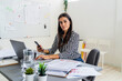 © Giorgio Fochesato/Westend61 - Confident female design professional sitting with wireless technologies at desk in office