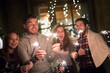 © HalfPoint/Westend61 - Happy friends holding sparklers outdoors at night