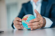 © Joseffson/Westend61 - Close-up of hands of businessman holding globe
