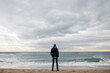 © JOSEP M ROVIROSA/Westend61 - Back view of man standing on the beach in winter looking at distance