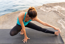 Young Woman Stretching On Exercise Mat At Promenade Against Sea