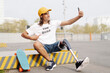 © joan corominas/Westend61 - Smiling disabled man taking selfie while sitting on road in city