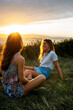 © Marco Govel/Westend61 - Smiling young woman spending leisure time with friend on field during sunset