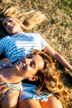 Cheerful Young Women Relaxing On Field During Sunny Day