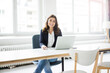 © Robijn Page/Westend61 - Portrait of happy businesswoman sitting at desk in the office working on laptop