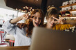 © KNSY/Westend61 - Two playful female friends with laptop in a cafe