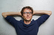© philipp nemenz/Westend61 - Portrait of smiling man with hands behind head wearing glasses