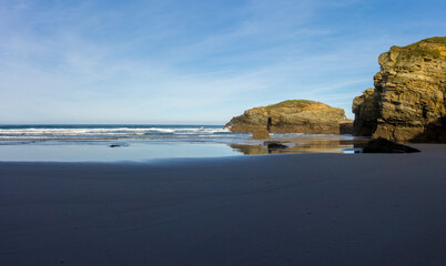 Sticker - warm golden evening on a sandy beach with jagged and rugged cliffs