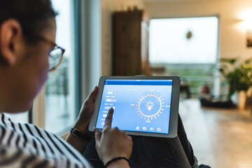 Woman using tablet with smart home control functions at home