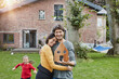 © Roger Richter/Westend61 - Portrait of smiling couple with daughter in garden of their home holding house model