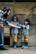 © Sofie Delauw/Westend61 - Father with two kids collecting eggs at chicken coop on an organic farm