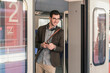 © Uwe Umst√§tter/Westend61 - Smiling young man with cell phone in commuter train