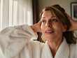 © Zeljko Dangubic/Westend61 - Close-up of smiling woman looking away with hands in blond hair at hotel room