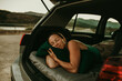 © David Molina Grande/Westend61 - Tired woman sleeping in cozy car trunk at dusk