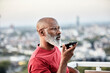 © Jo Kirchherr/Westend61 - Bald man talking through smart phone while standing at building terrace during sunset