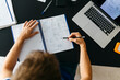 © JOSEP M ROVIROSA/Westend61 - Male student solving mathematical equations in workbook while sitting at table