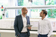 © BELLEVUE/Westend61 - Male professionals discussing while looking at each other in factory