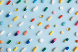Fototapeta Boho - Creative layout of colorful pills and capsules on blue background. Minimal medical concept. Pharmaceutical, Covid-19 or Coronavirus. Flat lay, top view