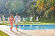 © ALTO IMAGES/Stocksy - Couple on holiday walking by the swimming pool