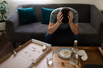 Depressed adult man sitting alone in front of food and alcohol