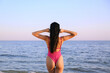 © New Africa - Young woman in pink stylish swimsuit on beach, back view