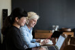 © Sofie Delauw/Stocksy - Cheerful diverse female entrepreneurs working on laptop in lobby
