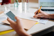 © Sofie Delauw/Stocksy - Crop freelancer using smartphone and making notes