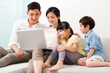 © Blue Jean Images - Cheerful young family using laptop at home