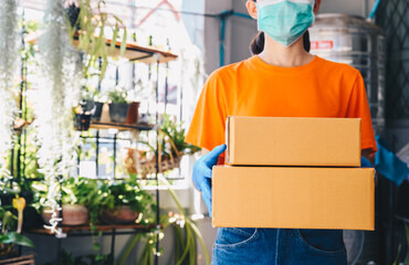 Delivery woman wearing an orange T-shirt, holding parcel boxes before delivering to customer. Conceptual shot of parcel delivery while working.