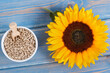 Sunflower seeds and beautiful vibrant flower on old boards background