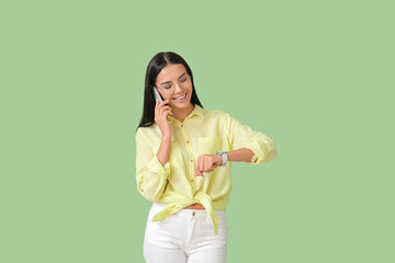 Poster - Young woman with wristwatch talking by phone on color background