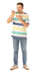 Poster - Young man eating wheatgrass on white background