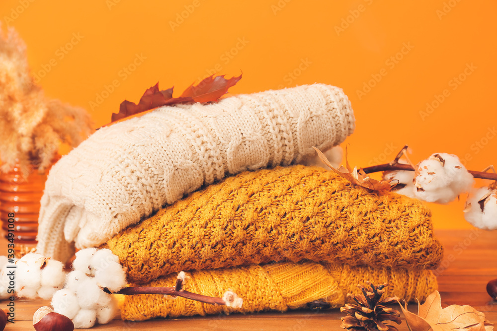Autumn composition with stylish clothes on table against color background